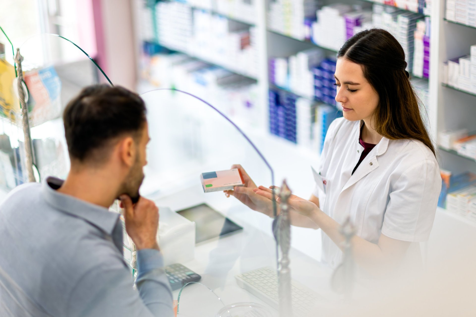 Cashier at the pharmacy store giving medicine at counter, explaining and recommending the medicine to the customer