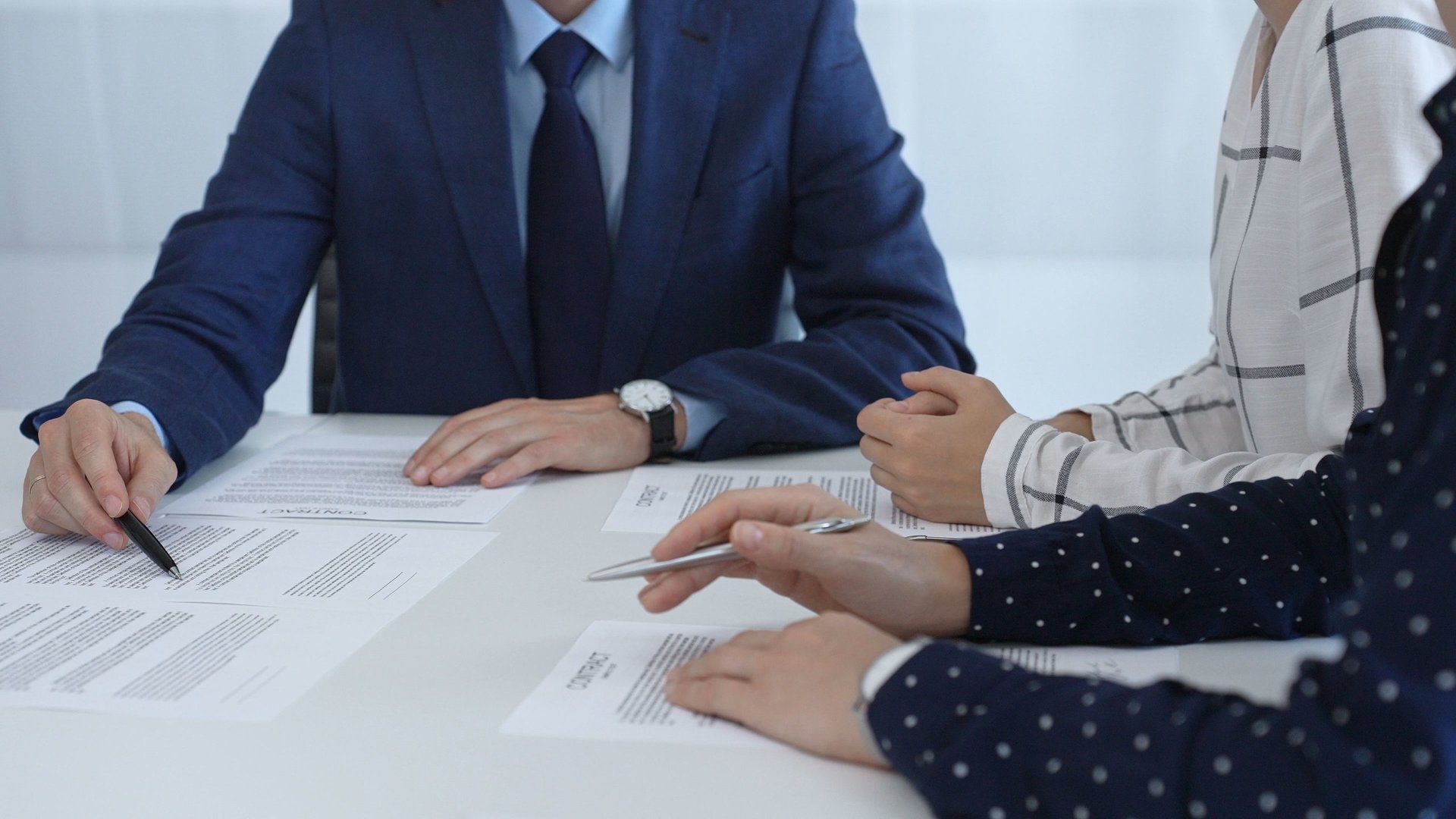 Business people reviewing contract during a meeting, pointing at specific clauses and discussing potential amendments before signing the agreement